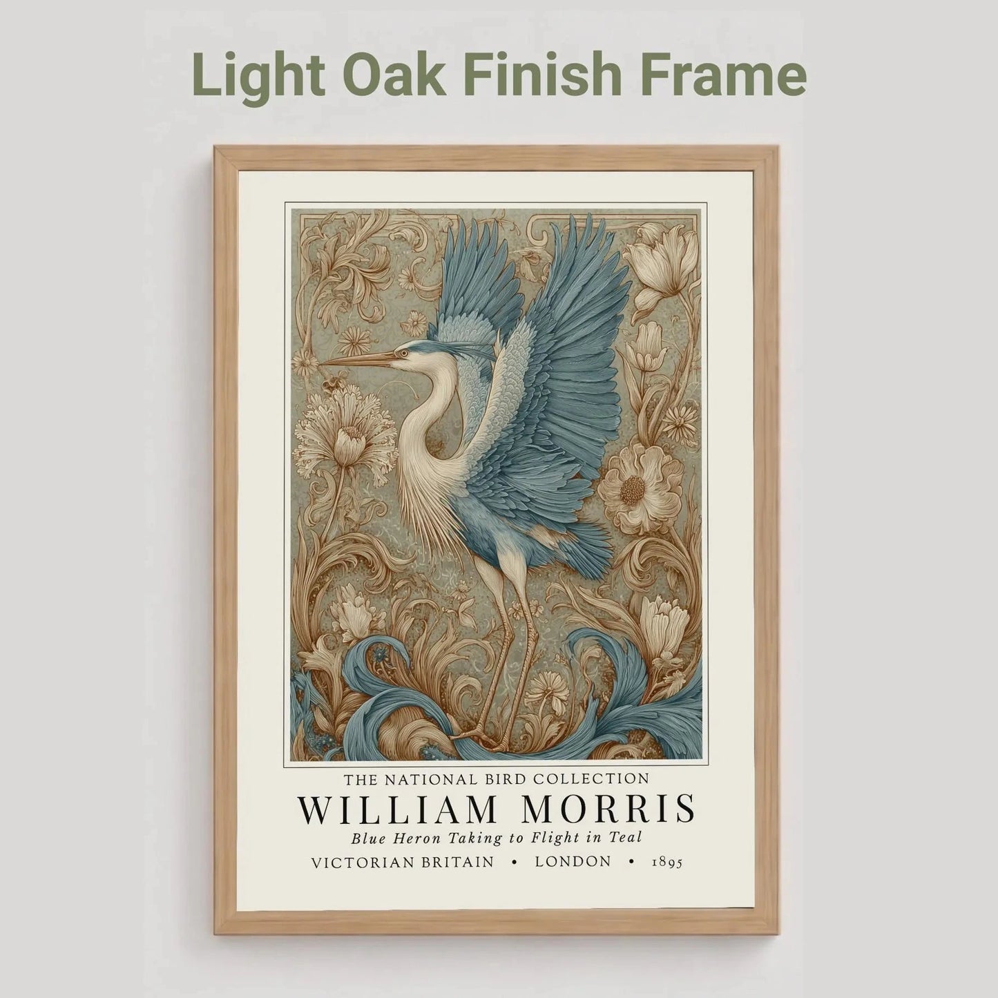 Oak finish framed artwork of a blue heron with decorative elements on a light gray background. William Morris style exhibition poster featuring a blue heron taking to flight, surrounded by ornate acanthus scrolls, dahlias and botanical foliage in teal, gold and antique cream — Arts & Crafts wall art print