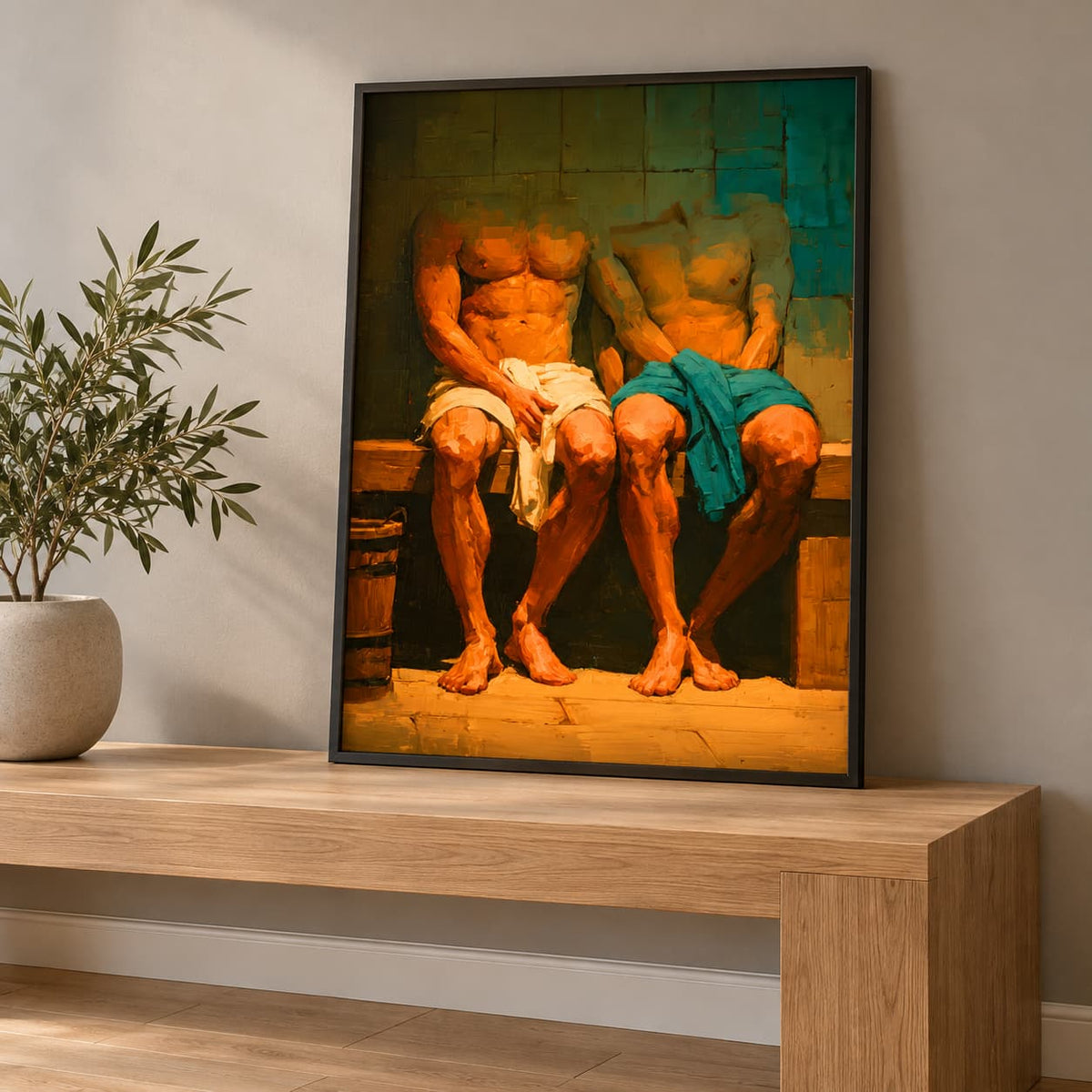 A framed art print depicting two shirtless men sitting on a bench, leaning against a wall on a light wood console table next to a potted plant.