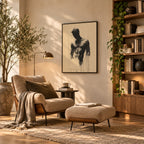 Bare Masculinity male figure print in a black frame on a cream wall in a reading nook with a boucle armchair, ottoman, floor lamp and bookshelves.
