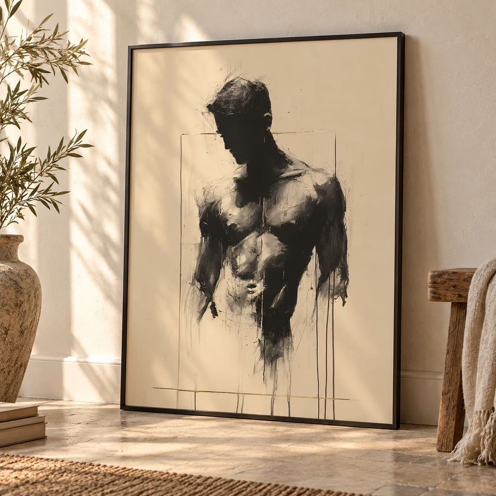 Bare Masculinity beige male figure print in a black frame, leaning against a cream wall beside an olive plant, books and a wooden stool.
