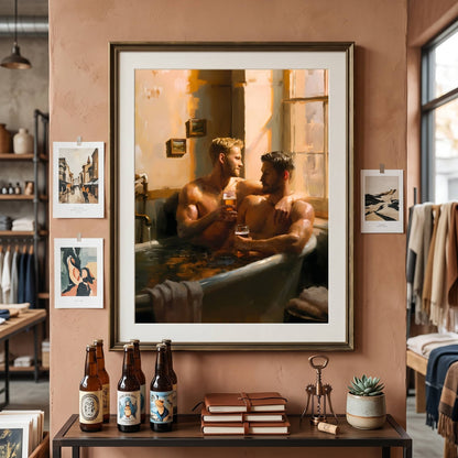 A framed art print depicting two men in a bathtub, hung on a warm terracotta wall in a styled room with other framed prints, beer bottles, and books on a table below.