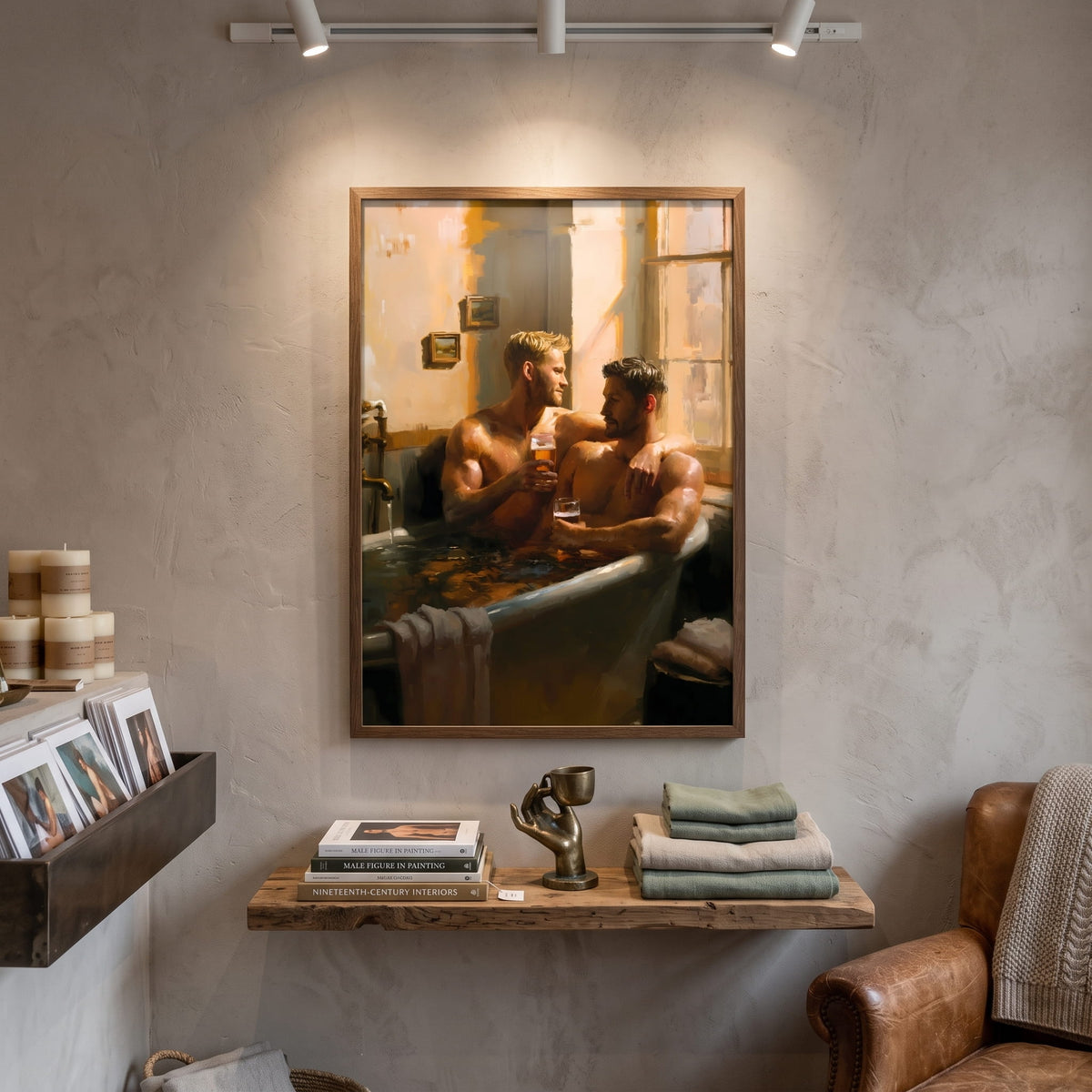 A framed art print depicting two men in a bathtub scene, displayed on a textured plaster wall in a styled room setting with a wooden shelf, books, and a leather armchair.