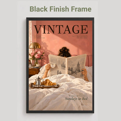 A framed vintage-style poster or magazine cover mockup on a light gray background, with the text 'Black Finish Frame' above it. The artwork shows a person reading in bed with a cup and toast, against a warm pink and peach background, with the word 'VINTAGE' prominently printed at the top.