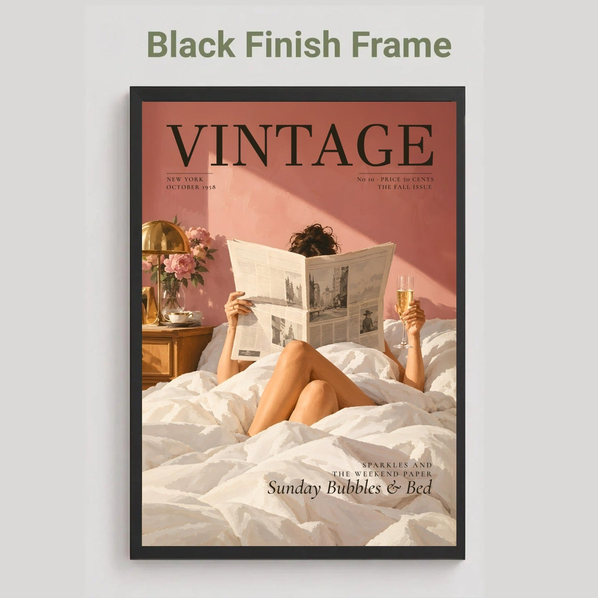 A framed vintage-style magazine cover art print on a light gray background. The poster shows a woman reading in bed under white sheets against a dusty pink wall, with the word VINTAGE prominently displayed at the top.