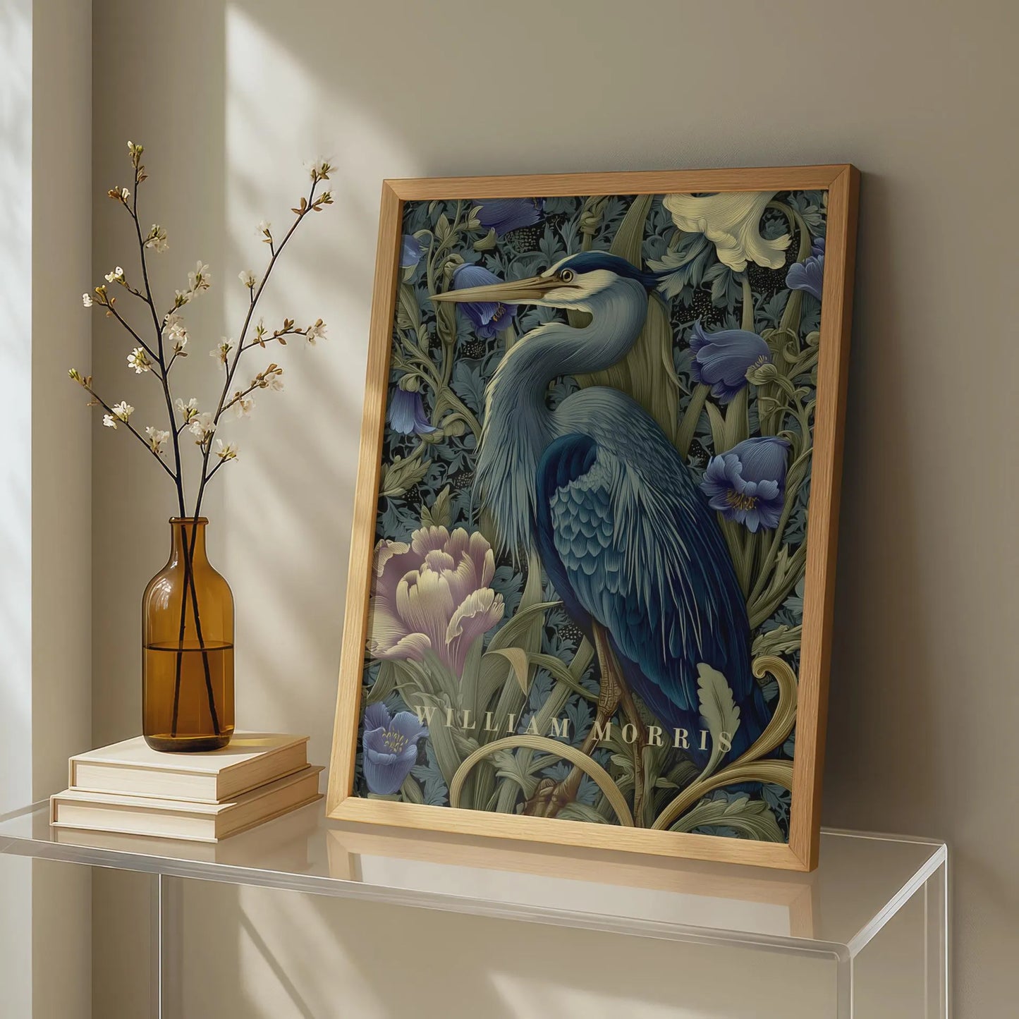 Framed artwork of a blue heron among flowers on a shelf with a vase and books. Blue heron among peonies and campanula in Victorian Arts & Crafts botanical style — dark teal, navy and olive art print