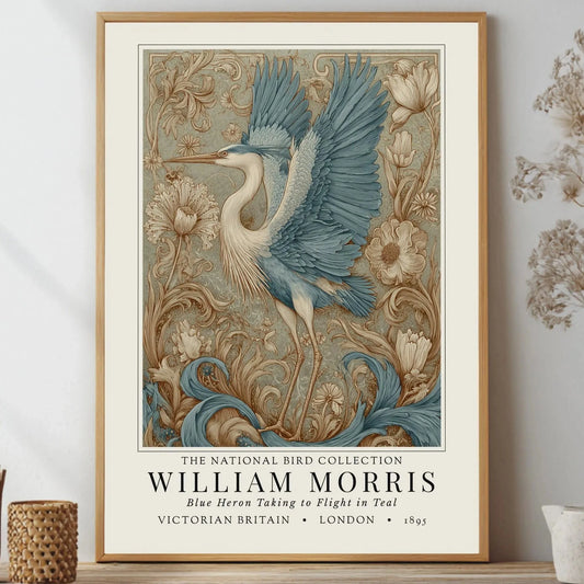 Framed artwork of a blue heron with floral elements on a wall. William Morris style exhibition poster featuring a blue heron taking to flight, surrounded by ornate acanthus scrolls, dahlias and botanical foliage in teal, gold and antique cream — Arts & Crafts wall art print