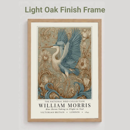 Oak finish framed artwork of a blue heron with decorative elements on a light gray background. William Morris style exhibition poster featuring a blue heron taking to flight, surrounded by ornate acanthus scrolls, dahlias and botanical foliage in teal, gold and antique cream — Arts & Crafts wall art print