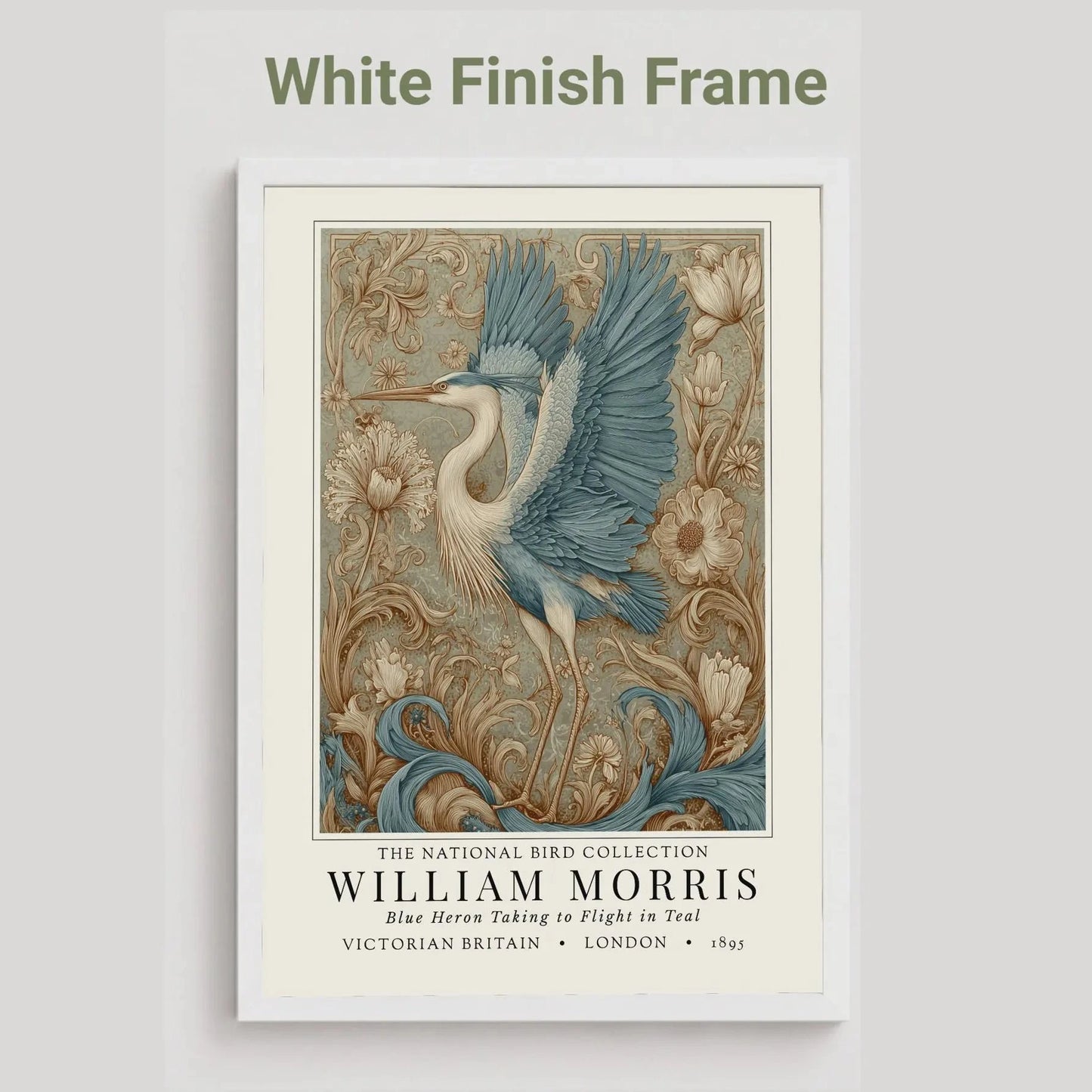 White framed artwork of a blue heron with decorative elements on a light gray background. William Morris style exhibition poster featuring a blue heron taking to flight, surrounded by ornate acanthus scrolls, dahlias and botanical foliage in teal, gold and antique cream — Arts & Crafts wall art print