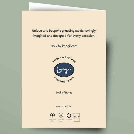A cream-colored greeting card shown flat against a muted sage green background. The card features black text and a dark blue oval logo for 'imagii Greeting Cards'.