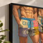Close-up of the black frame corner on the Cool Boys print, showing the brushwork on the bare-chested figures and their pastel patchwork COOL shorts against a textured white wall.