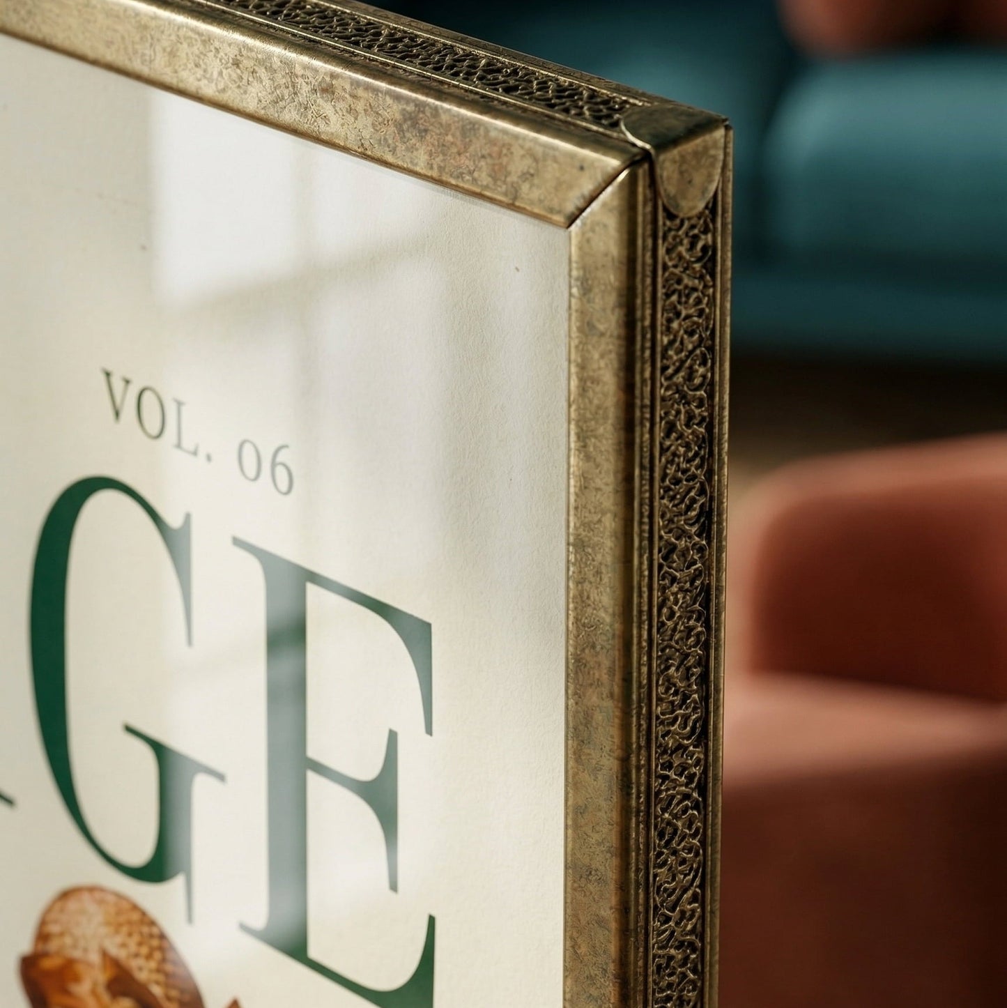 Framed book or magazine cover with decorative gold frame, blurred sofa in the background