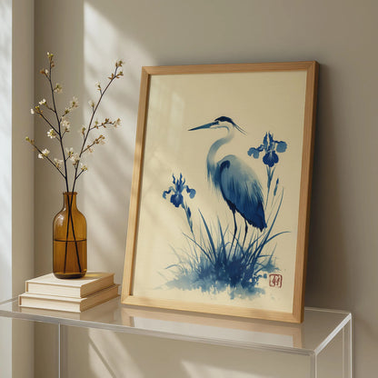 Framed artwork of a blue heron and iris flowers on a shelf with a vase and books.Blue heron and water iris sumi-e print in indigo and cream — Japanese watercolour wall art with cinnabar seal