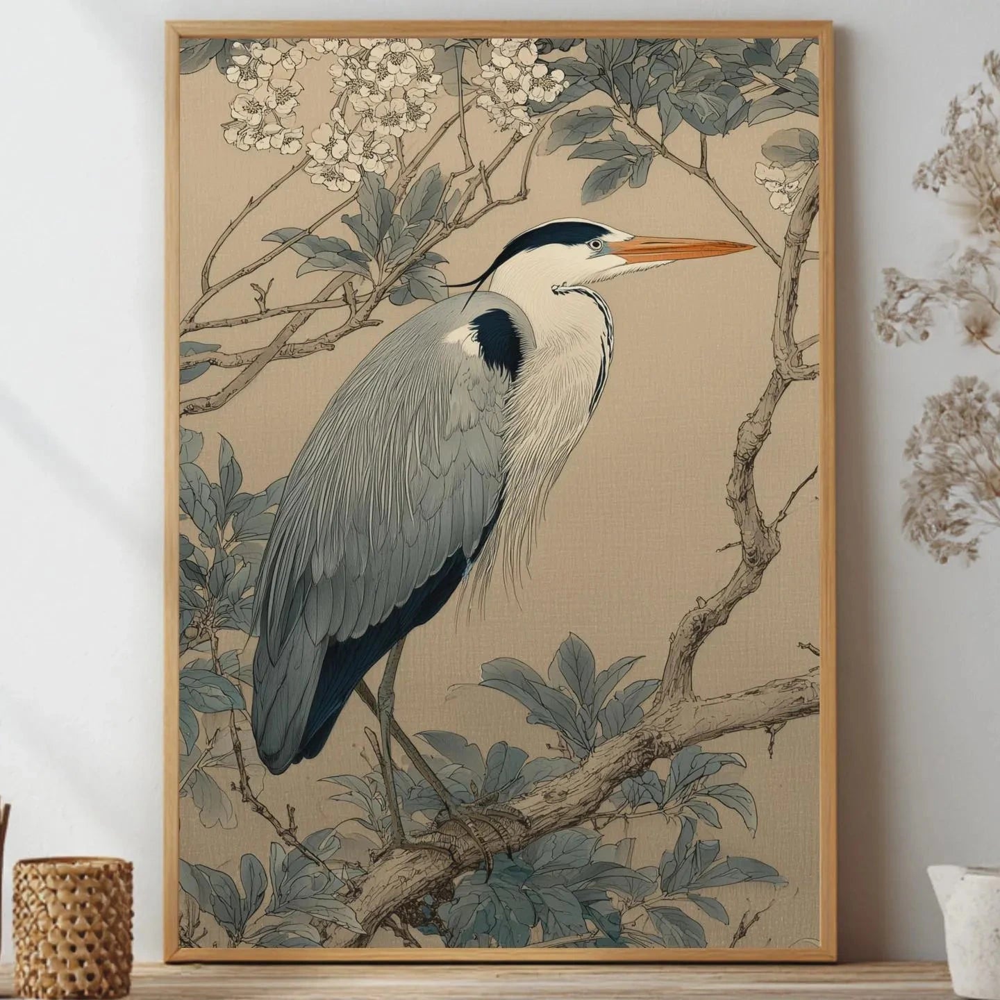 Framed artwork of a heron on a branch with flowers, displayed on a wall.