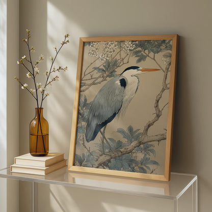 Framed artwork of a heron on a table with a vase and books.