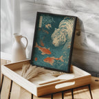 Framed artwork of a tiger and goldfish on a wooden tray with a white vase in the background. Japanese woodblock-style art print of a white tiger gazing into a teal koi pond, with three orange koi fish swimming in the foreground, cherry blossoms, lush foliage, and traditional Japanese calligraphy seals, in a deep teal and burnt-orange palette.
