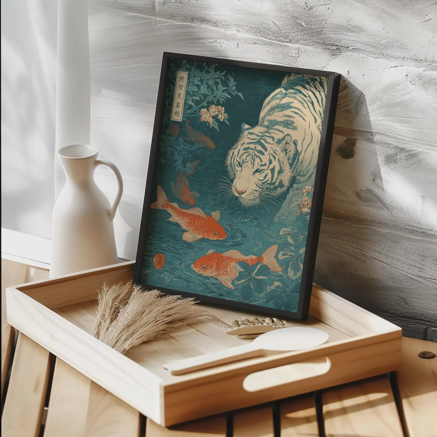 Framed artwork of a tiger and goldfish on a wooden tray with a white vase in the background. Japanese woodblock-style art print of a white tiger gazing into a teal koi pond, with three orange koi fish swimming in the foreground, cherry blossoms, lush foliage, and traditional Japanese calligraphy seals, in a deep teal and burnt-orange palette.