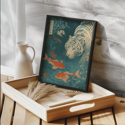 Framed artwork of a tiger and goldfish on a wooden tray with a white vase in the background. Japanese woodblock-style art print of a white tiger gazing into a teal koi pond, with three orange koi fish swimming in the foreground, cherry blossoms, lush foliage, and traditional Japanese calligraphy seals, in a deep teal and burnt-orange palette.