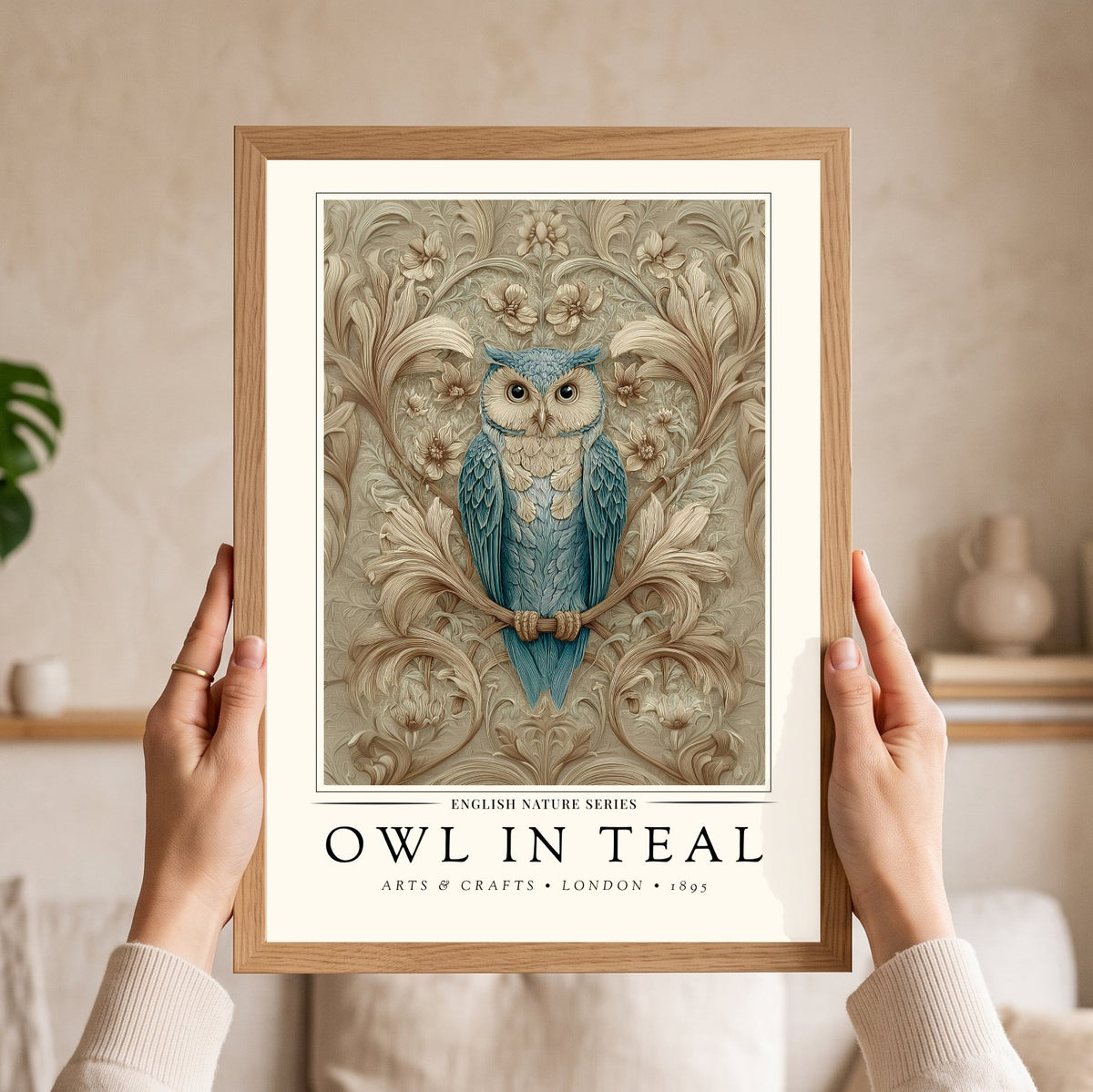 A person holds a framed art print featuring a blue owl on a branch with ornate floral scrollwork. The print has a light wood frame and the text 'OWL IN TEAL' with 'English Nature Series' and 'Arts & Crafts London 1893' visible.