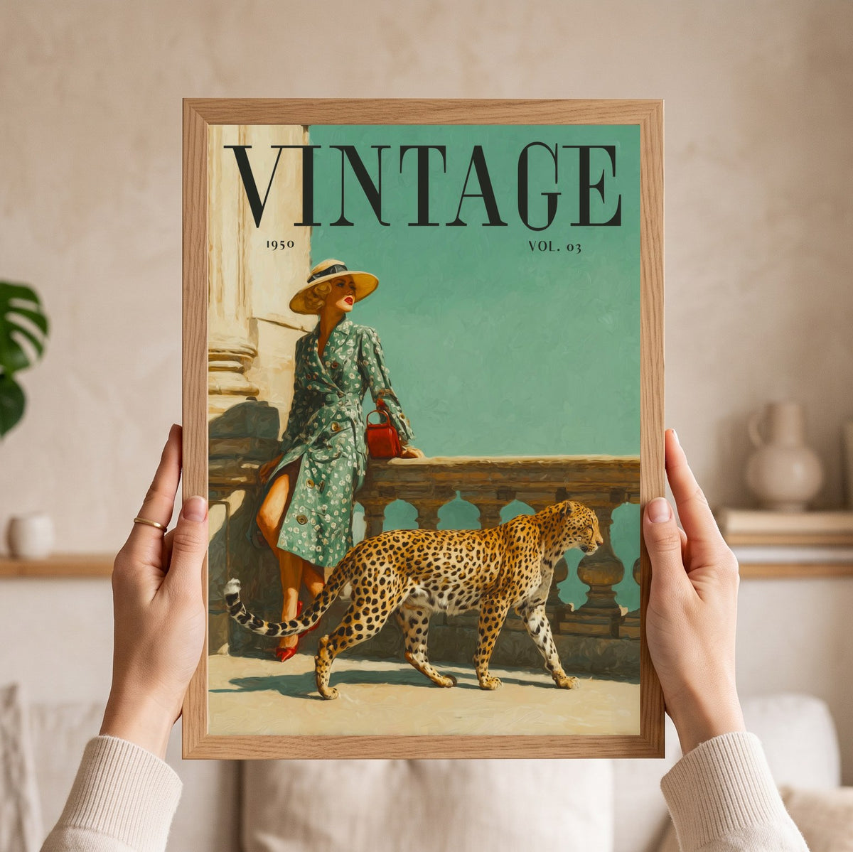 A person holds a framed vintage-style art print featuring a woman in a green patterned dress and a leopard on a teal background. The print has the word VINTAGE at the top and is shown in a light wood frame against a softly blurred indoor setting.