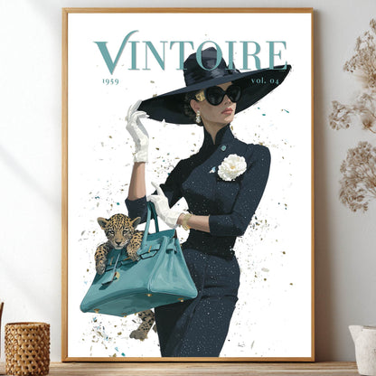 A framed fashion poster featuring a woman in a black hat and dark outfit holding a turquoise handbag, styled on a shelf with dried flowers and decorative objects in a home interior.