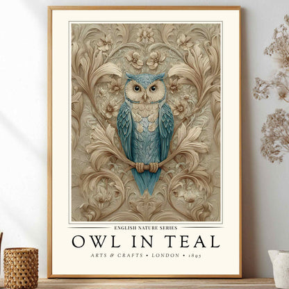 A framed art print featuring a blue owl perched on a branch against an ornate beige floral background, with the text 'OWL IN TEAL' and 'ARTS & CRAFTS • LONDON • 1893' below. The print is displayed leaning against a white wall on a shelf, surrounded by decorative dried flowers and small vessels.