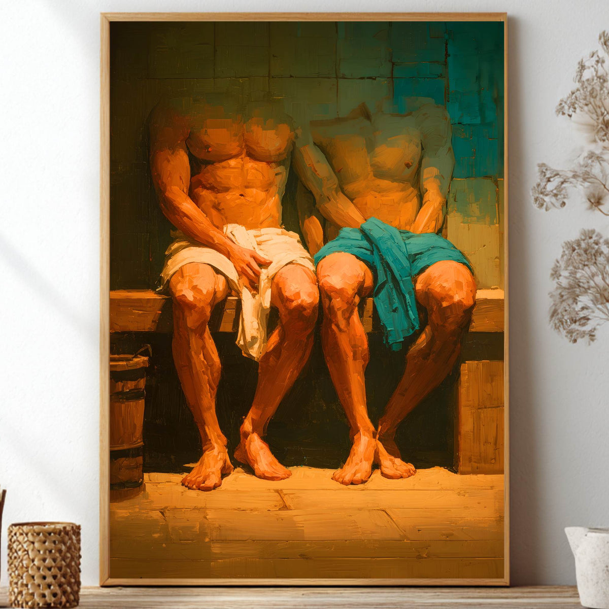 A framed art print depicting two muscular men sitting on a bench, one wrapped in a white cloth and the other in a teal-blue cloth, displayed on a shelf in a styled room setting.