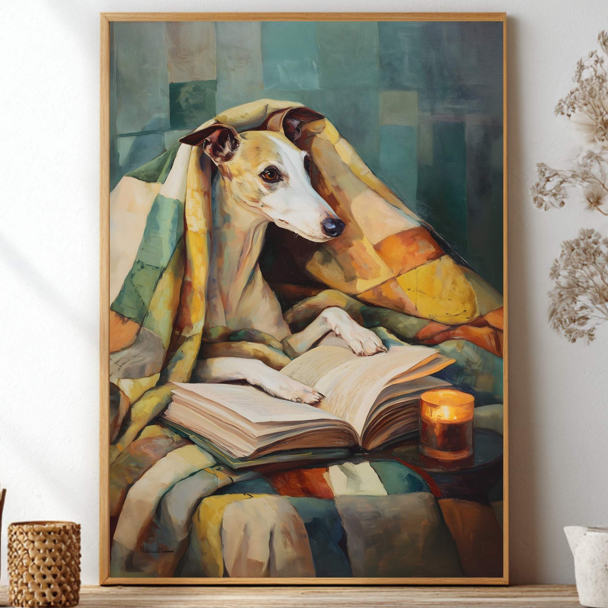 A framed vertical art print depicting a white and tan dog wrapped in a colorful blanket while reading a book, displayed on a shelf in a styled interior setting with dried flowers and small decorative vases.