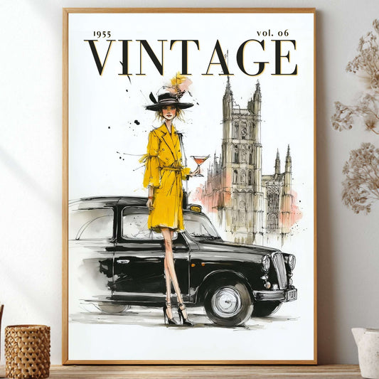 A framed vintage-style art print featuring a woman in a bright yellow coat and hat standing beside a black car, with a tower in the background and the word 'VINTAGE' at the top. The framed print is displayed on a shelf against a light wall with dried flowers and small decor items around it.
