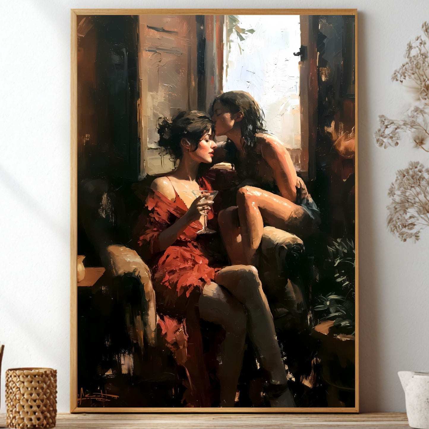 A framed vertical art print depicting a romantic scene of two women embracing by a window, styled on a shelf with dried flowers and decorative vases.