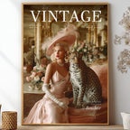 A framed vintage-style art print featuring a woman in a pale pink gown and feathered hat seated beside a leopard, styled on a shelf with dried flowers and decorative vases in a bright interior.