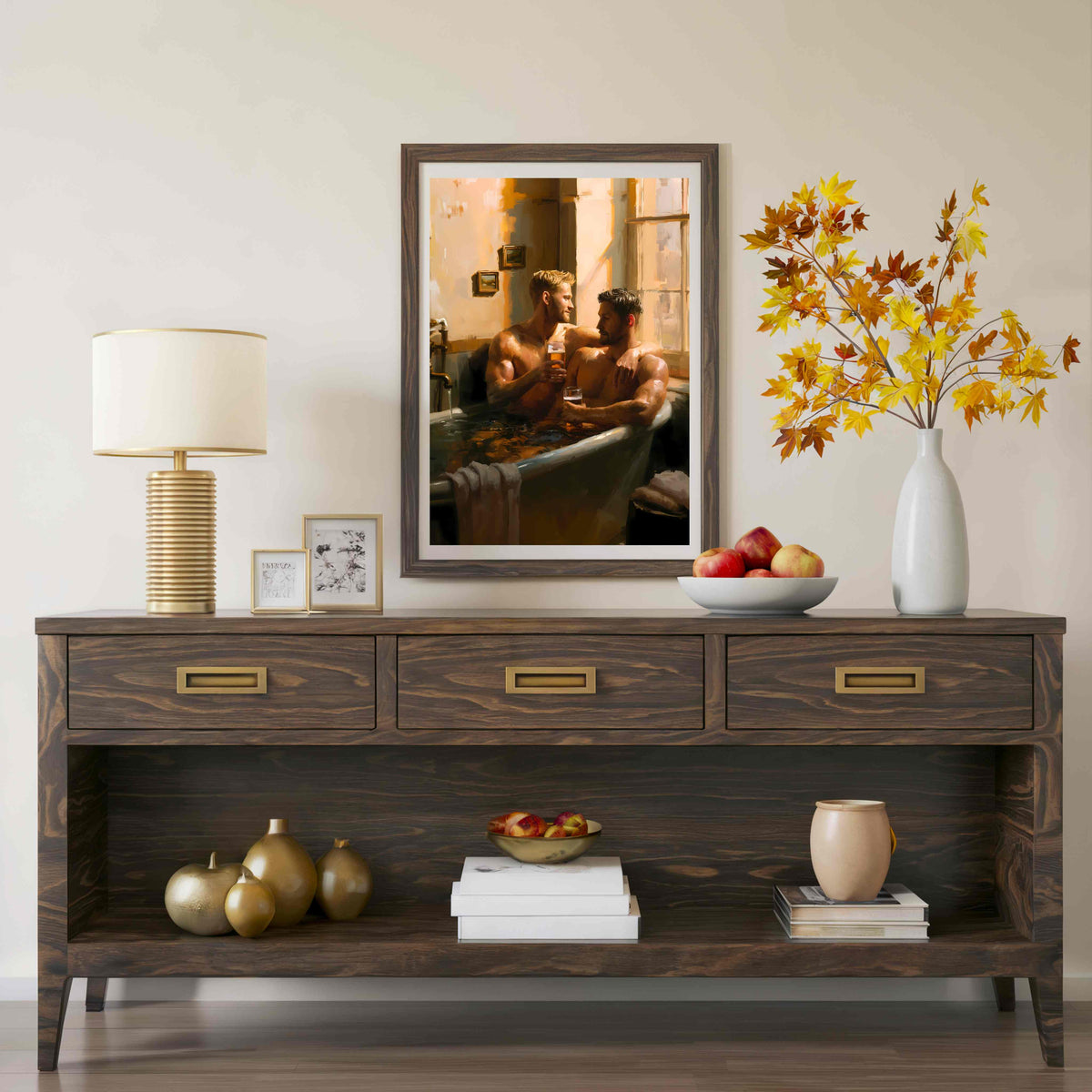 A framed art print depicting a couple in a warm-toned bathroom scene, displayed on a dark wood console table in a styled room setting with a lamp, bowls, and a vase of autumn leaves.