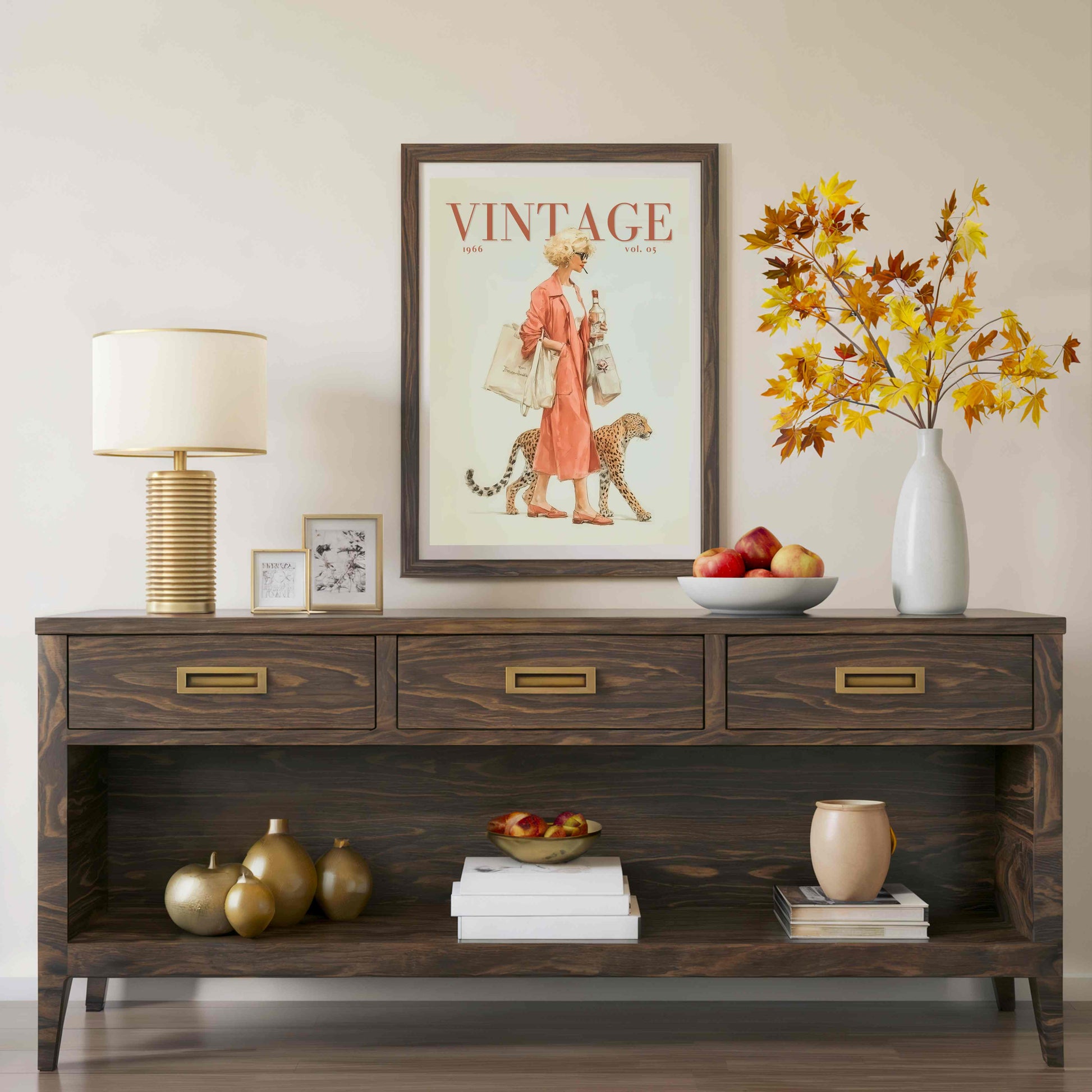 A dark brown wooden console table styled in a living room setting, featuring a lamp, framed art, a vase with autumn leaves, and decorative objects on and below it.
