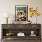 A dark wood console table styled in a living room setting, featuring a framed painting of a dog reading, a table lamp, decorative vases, and fruit bowls.