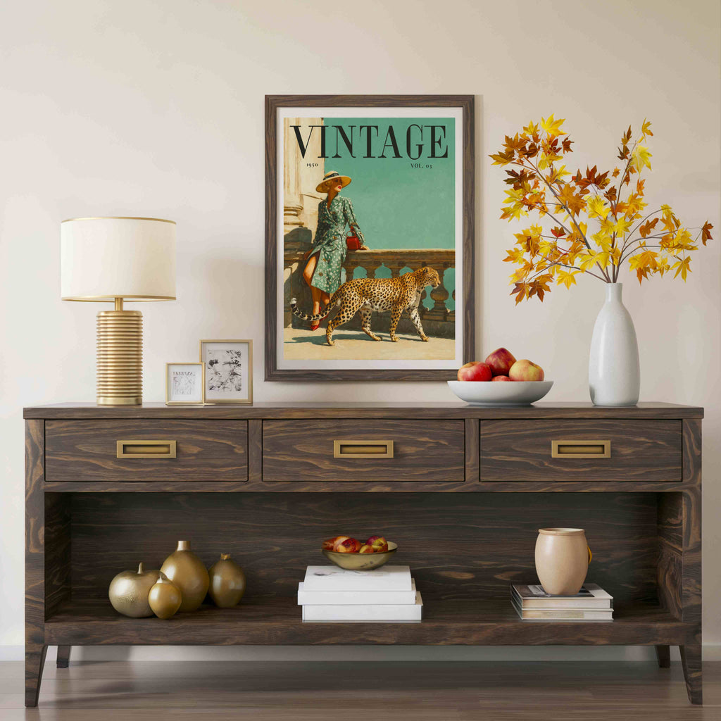 A framed vintage-style magazine cover print hangs on a beige wall above a dark wood console table. The print shows a woman walking a cheetah with the word 'VINTAGE' at the top.