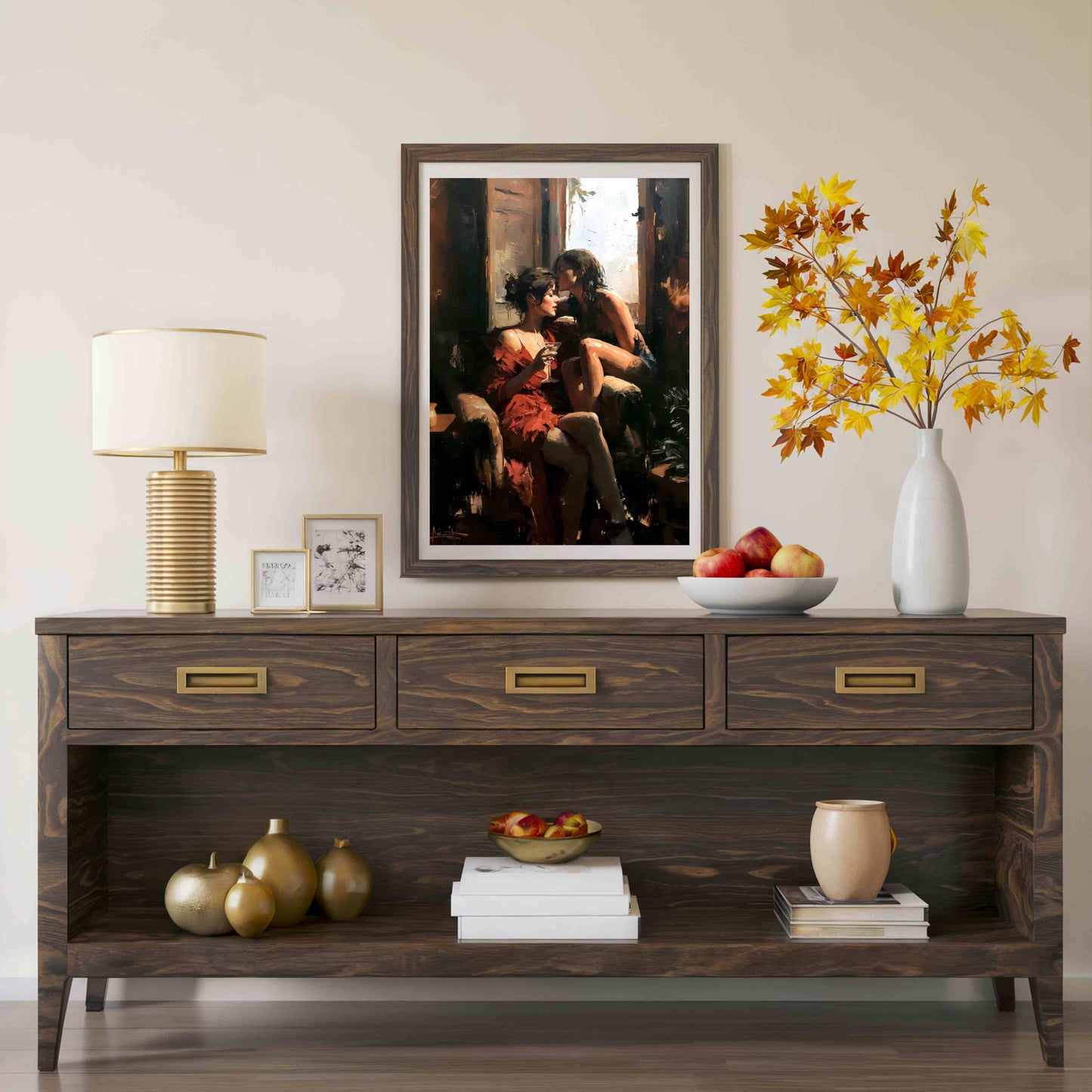 A dark brown wooden console table styled in a living room setting, featuring a large framed art print of a couple on the wall above it. The table is decorated with a lamp, small frames, a bowl of apples, a vase with autumn leaves, and decorative gourds.