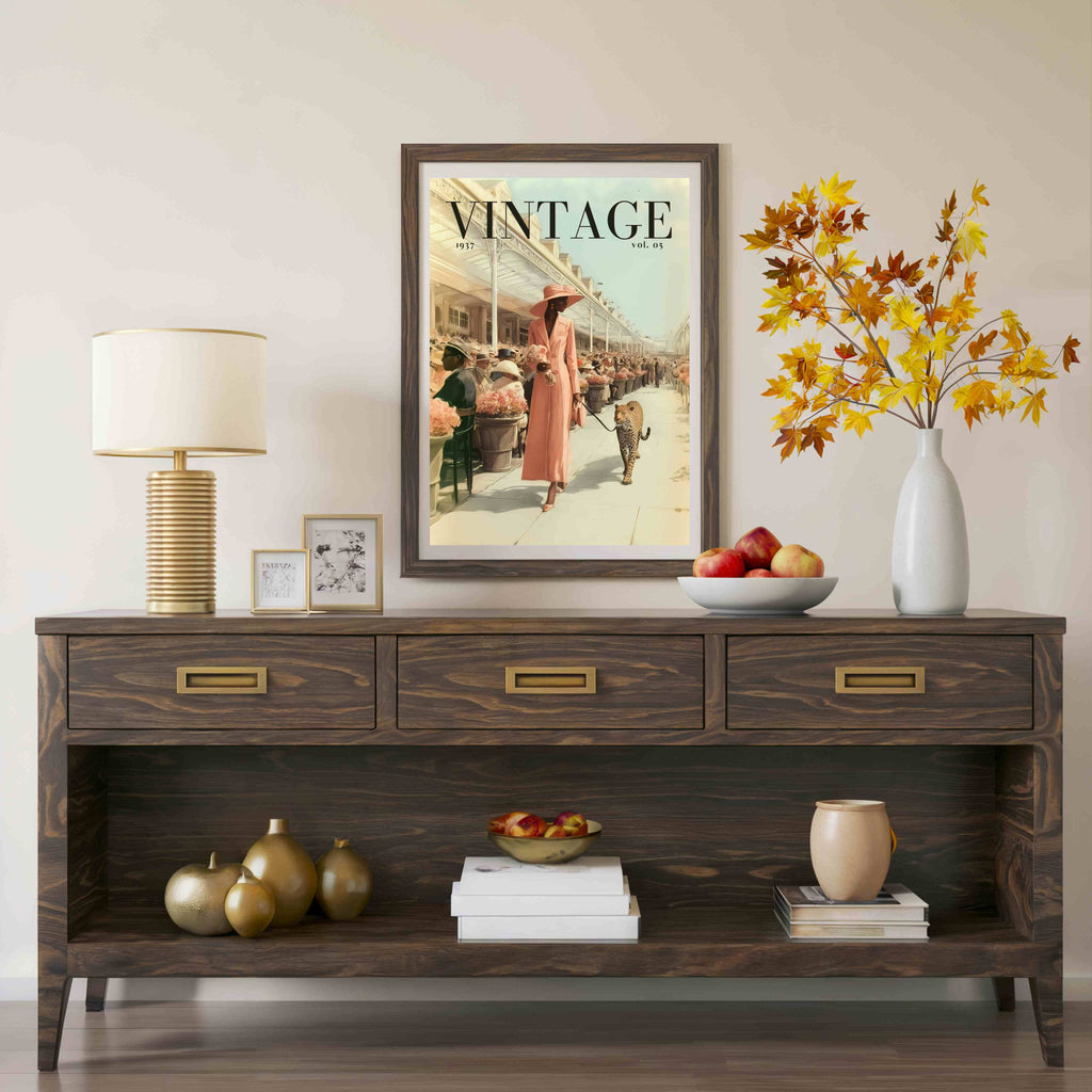 A dark brown wooden console table styled in a living room setting, featuring a vintage 'Vintage' magazine poster hanging above it, a table lamp, decorative vases, and fruit bowls.