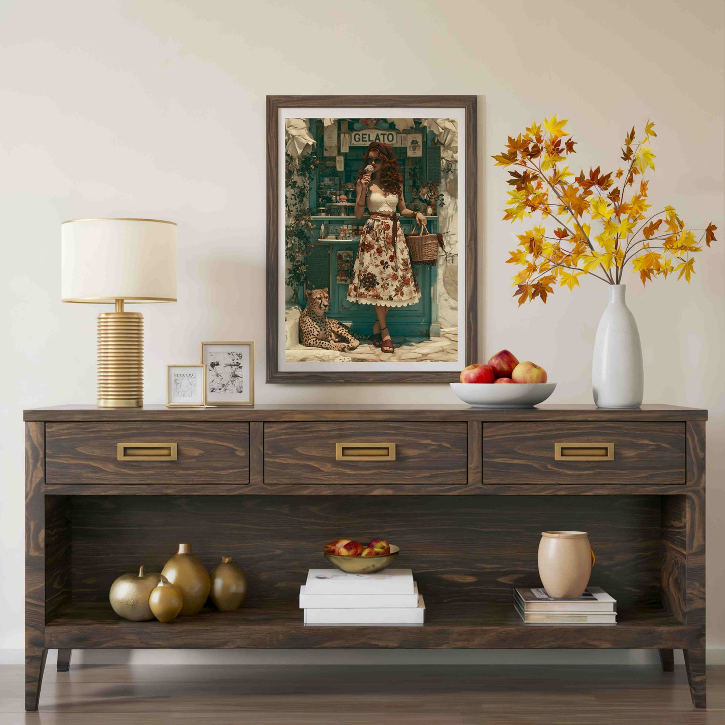 A dark wood console table styled in a living room setting, featuring three drawers with brass handles, an open lower shelf, and decorative items including a lamp, framed art, a vase of autumn leaves, and fruit. Vintage, maximalist, eclectic wall art.