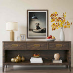 A dark wood console table styled in a living room setting, featuring a framed portrait of a dog, a table lamp, a vase with autumn leaves, and decorative objects on and below the table.