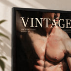 Close-up of the black-framed Vintage The Modern Man print showing the VINTAGE masthead, New York Edition August 1957 line and the bare-chested male torso, hanging on a light wall beside a plant shadow.