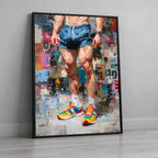 A framed vertical art print leaning against a light gray wall on a pale wood floor. The artwork depicts a cropped figure from the waist down wearing blue shorts and bright multicolor sneakers, rendered in an expressive painterly style.