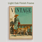 A framed vintage-style art print featuring a woman in a green patterned dress sitting on a balcony with a leopard walking in front of her, set in a light oak frame against a light gray background. Text above reads 'Light Oak Finish Frame'.