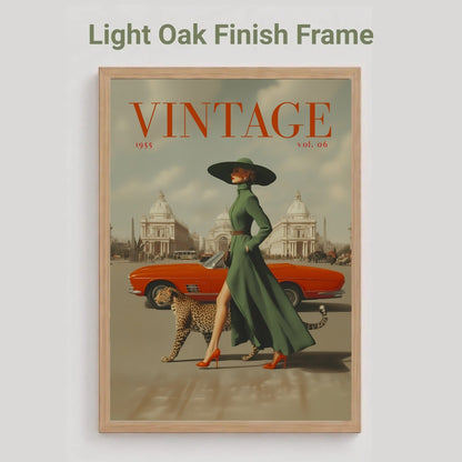 A framed vintage-style art print with a light oak finish frame, featuring an illustration of a woman in a green dress and black hat walking beside an orange convertible car and a leopard, with the word 'VINTAGE' at the top. The image is shown on a light gray background with the text 'Light Oak Finish Frame' above it.