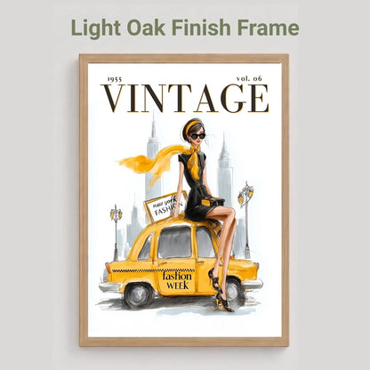A framed vintage-style art print featuring a woman sitting on a yellow taxi with the word VINTAGE prominently displayed, shown against a light gray background with the text 'Light Oak Finish Frame' above it.