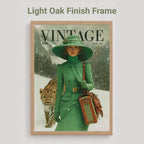 A framed vintage-style poster or magazine cover print hangs on a light gray wall. The artwork shows a woman in a green coat and wide-brim green hat walking in the snow with a leopard, and the word VINTAGE appears at the top.