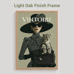 A framed art print featuring a vintage fashion illustration with the title 'VINTOIRE' and a cat, shown against a light gray background with the text 'Light Oak Finish Frame' above it.
