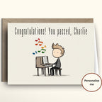 Greeting card with a cartoon illustration of a person sitting at a piano, with text 'Congratulations! You passed, Charlie'.