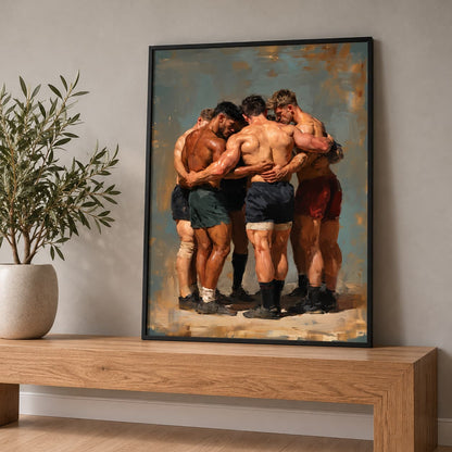 A framed art print depicting five rugby players hugging, displayed on a wooden console table next to a potted plant against a neutral gray wall.