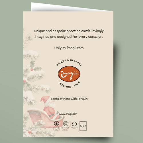 A single greeting card shown flat against a muted sage green background. The card has a cream front with printed holiday illustrations along the left side, including pine branches, holly, and a pink sleigh.