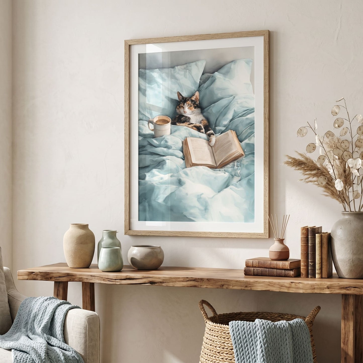 Watercolor print of a calico cat sleeping in bed beside an open book and cream coffee mug on soft mint bedding, cozy bedroom wall art.