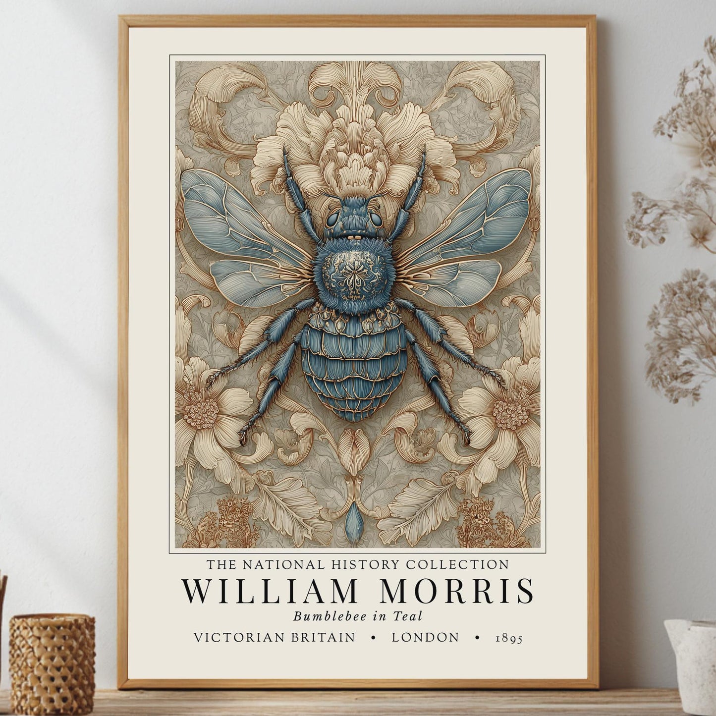A framed William Morris art print featuring a detailed blue and beige bumblebee illustration, styled on a shelf with dried botanicals and small decorative vases against a light gray wall.